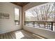 Covered porch featuring wood flooring, a metal railing, and views of mature trees at 3700 Baron Cooper Pass # 104, Raleigh, NC 27612