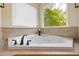 Corner soaking tub features tile trim, a window, and a black faucet against a neutral wall at 3729 Norman Blalock Rd, Willow Springs, NC 27592