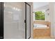 Well-lit bathroom with tile flooring features a glass shower and a soaking tub with a window at 3729 Norman Blalock Rd, Willow Springs, NC 27592