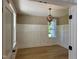 A dining room with hardwood floors, decorative wainscotting, and a modern lighting fixture at 5480 Thom Rd, Mebane, NC 27302