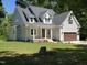 Charming two-story home with a covered front porch, lush green lawn, and attached two-car garage at 5480 Thom Rd, Mebane, NC 27302