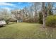 Large, grassy backyard featuring mature trees, flowering bushes and a storage shed at 5604 Stardust Dr, Durham, NC 27712