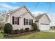 Side view of the home showing siding, windows with shutters, professional landscaping and a two-car garage at 5604 Stardust Dr, Durham, NC 27712