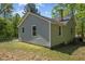 Rear view of home with black roof, light gray vinyl siding, and green grass at 5864 Whitney Rd, Graham, NC 27253