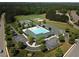 Aerial view of the community pool and clubhouse with sports fields, tennis courts, and parking at 7 Brandon Pines Ct, Pittsboro, NC 27312