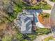An aerial view showing the layout of the house, driveway, and manicured landscaping with many mature trees at 702 Orange Ct, Elon, NC 27244