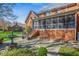 Back exterior view features brickwork, a screened porch, landscaping, and a stone patio with fountain at 702 Orange Ct, Elon, NC 27244