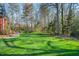 Expansive backyard featuring lush green grass and mature trees and a well-manicured lawn at 702 Orange Ct, Elon, NC 27244