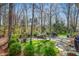 Lush backyard with mature trees, landscaping, stone features and a swing, creating a serene retreat at 702 Orange Ct, Elon, NC 27244