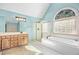 Bright bathroom features a soaking tub, glass enclosed shower, and light blue walls at 702 Orange Ct, Elon, NC 27244