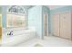 Bright bathroom featuring a soaking tub, white tile, and a double door closet at 702 Orange Ct, Elon, NC 27244