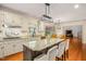Spacious kitchen with granite countertops, island with chairs, wood floors, and open view to living area at 702 Orange Ct, Elon, NC 27244