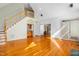 Open living room with hardwood floors, wet bar, and staircase to second floor with natural light at 702 Orange Ct, Elon, NC 27244