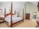Spacious bedroom features a four-poster bed, light carpeting, and a view into the bathroom at 702 Orange Ct, Elon, NC 27244