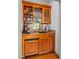 A close-up of the wet bar featuring custom cabinetry, granite countertops, a beverage fridge and glass shelving at 702 Orange Ct, Elon, NC 27244