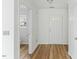 Hallway featuring hardwood floors, white walls, and access to a bathroom and front door at 707 Obsidian Way, Durham, NC 27703