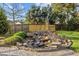Landscaped backyard featuring a rock waterfall, beautiful trees, lush grass, and a wooden fence for privacy at 814 Ember Dr, Durham, NC 27703