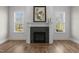 Cozy fireplace with black tile surround, flanked by windows, and complemented by hardwood floors at 818 St Charles St, Durham, NC 27713