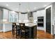 Bright, modern kitchen featuring white cabinets, stainless steel appliances, and a gray island with bar stool seating at 853 Rambling Oaks Ln, Holly Springs, NC 27540
