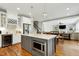 Open-concept kitchen featuring an island with gray cabinetry, a microwave, and a view to the dining and living rooms at 853 Rambling Oaks Ln, Holly Springs, NC 27540