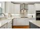 Bright, modern kitchen featuring white cabinets, stainless steel appliances, and stone tile backsplash at 853 Rambling Oaks Ln, Holly Springs, NC 27540
