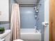 Bathroom with a white bathtub, shower with blue tiling, toilet, and neutral-colored shower curtain at 104 Black Cloud Dr, Louisburg, NC 27549