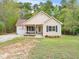 A charming single-story home with a well-manicured lawn and inviting front porch, surrounded by lush trees at 104 Black Cloud Dr, Louisburg, NC 27549