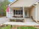 Charming front porch with seating area and an American flag displayed on a beige, single-story home at 104 Black Cloud Dr, Louisburg, NC 27549
