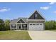 Charming home showcasing a stone-accented two-car garage, gray siding, and a well-manicured lawn on a sunny day at 106 S Harper Faith Way, Benson, NC 27504