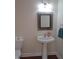 Well-lit bathroom with a pedestal sink, decorative mirror, and a neutral color scheme at 109 Bright Shade Ct, Holly Springs, NC 27540