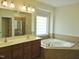 Bathroom featuring a double sink vanity, a glass block window, and a tiled soaking tub at 109 Bright Shade Ct, Holly Springs, NC 27540