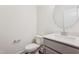 Modern half bath with white toilet, a vanity with a round mirror, and light gray cabinets at 111 Artic Circle, Garner, NC 27529