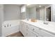 Bathroom with double sinks, white cabinets, large mirror, and separate tub at 121 Viajar Way, Smithfield, NC 27577