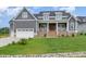 Charming gray two-story home with brick accents, covered porch, and well-manicured lawn at 1221 Azalea Garden Cir, Raleigh, NC 27603