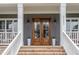 Inviting entryway with double wooden doors, brick steps, and classic white columns at 1221 Azalea Garden Cir, Raleigh, NC 27603