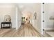 Bright hallway featuring light wood floors and a glimpse of the living room with fireplace at 1221 Azalea Garden Cir, Raleigh, NC 27603