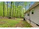 View of the side of a home with a lush wooded backyard with green grass at 1332 Stallings Rd, Chapel Hill, NC 27516