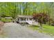 Charming home featuring light gray siding, a welcoming front porch, and a gravel driveway surrounded by lush greenery at 1332 Stallings Rd, Chapel Hill, NC 27516