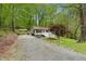 Charming home featuring light gray siding, a welcoming front porch, and a gravel driveway surrounded by lush greenery at 1332 Stallings Rd, Chapel Hill, NC 27516