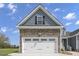 Garage exterior featuring a stone facade, carriage-style doors, and dormer window above at 163 S Harper Faith Way, Benson, NC 27504