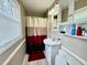 This renovated bathroom offers a shower with neutral shower curtain, vinyl flooring and white vanity at 1802 Greenbriar Rd, Henderson, NC 27536