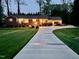 Exterior view of a well-lit home at dusk featuring a long driveway and manicured lawn at 1802 Greenbriar Rd, Henderson, NC 27536