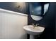 Stylish powder room featuring a pedestal sink, oval mirror, beadboard paneling and dark blue accent wall at 192 Solheim Ln, Raleigh, NC 27603