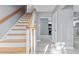 Bright hallway with hardwood stairs and gray walls leading to the kitchen with stainless steel appliances at 204 N Gurney St, Burlington, NC 27215