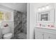 Bright bathroom featuring a vanity with storage, framed mirror, and tiled walk-in shower with window at 226 1St St, Henderson, NC 27536