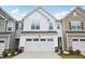 Charming two-story townhouse with a white exterior, attached garage, stone accents, and well-manicured landscaping at 272 Hiking Hill Ln, Garner, NC 27529