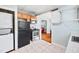 Kitchen with stacked washer/dryer and black refrigerator next to oven, microwave, and open dining room view at 2724 N Roxboro St, Durham, NC 27704