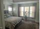 Serene main bedroom featuring a large bed, tray ceiling, hardwood floors, and plenty of natural light at 338 Apalachia Lake Dr, Fuquay Varina, NC 27526