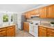 Efficient kitchen with wood cabinets, laminate countertops, white appliances, and ample natural light at 3421 E Jameson Rd, Raleigh, NC 27604