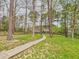 Spacious backyard with mature trees, lush lawn, and a wooden pathway, perfect for outdoor enjoyment at 3705 Andoversford Ct, Wake Forest, NC 27587